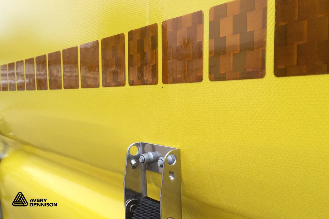 Close-up of a yellow surface with metallic accents and Avery Dennison logo.