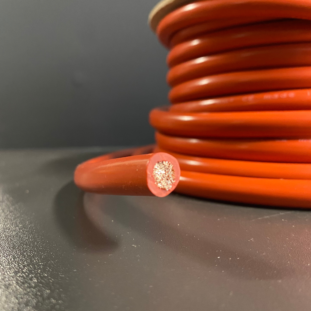 A close-up of bright orange electrical cable, with one end cut to show the multi-strand copper wire core, set against a dark gray background.