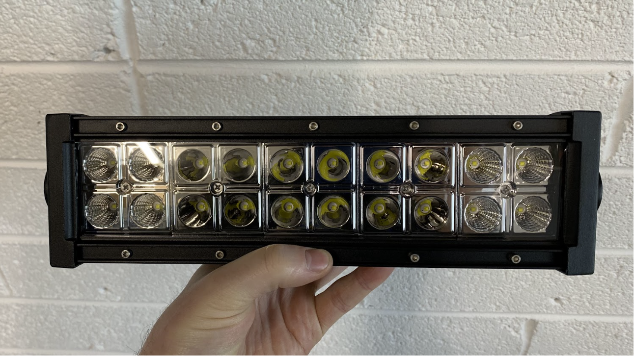 Hand holding a rectangular LED light bar against a tiled wall background