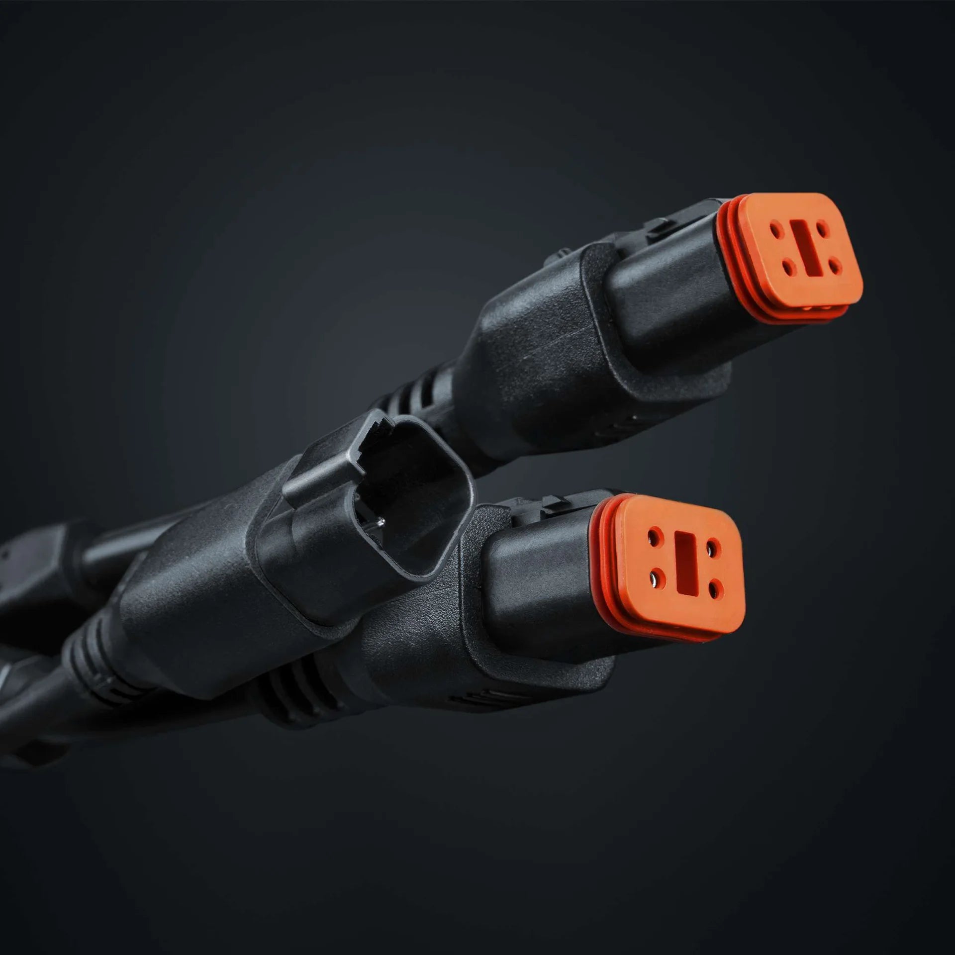 Two black cables with orange connectors on a dark background