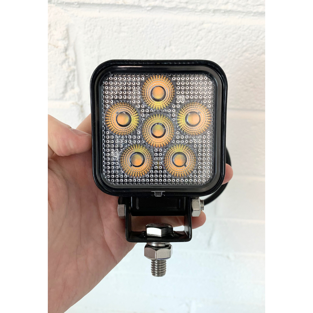 Hand holding a square LED work light with multiple bulbs on a white background UK + Ireland